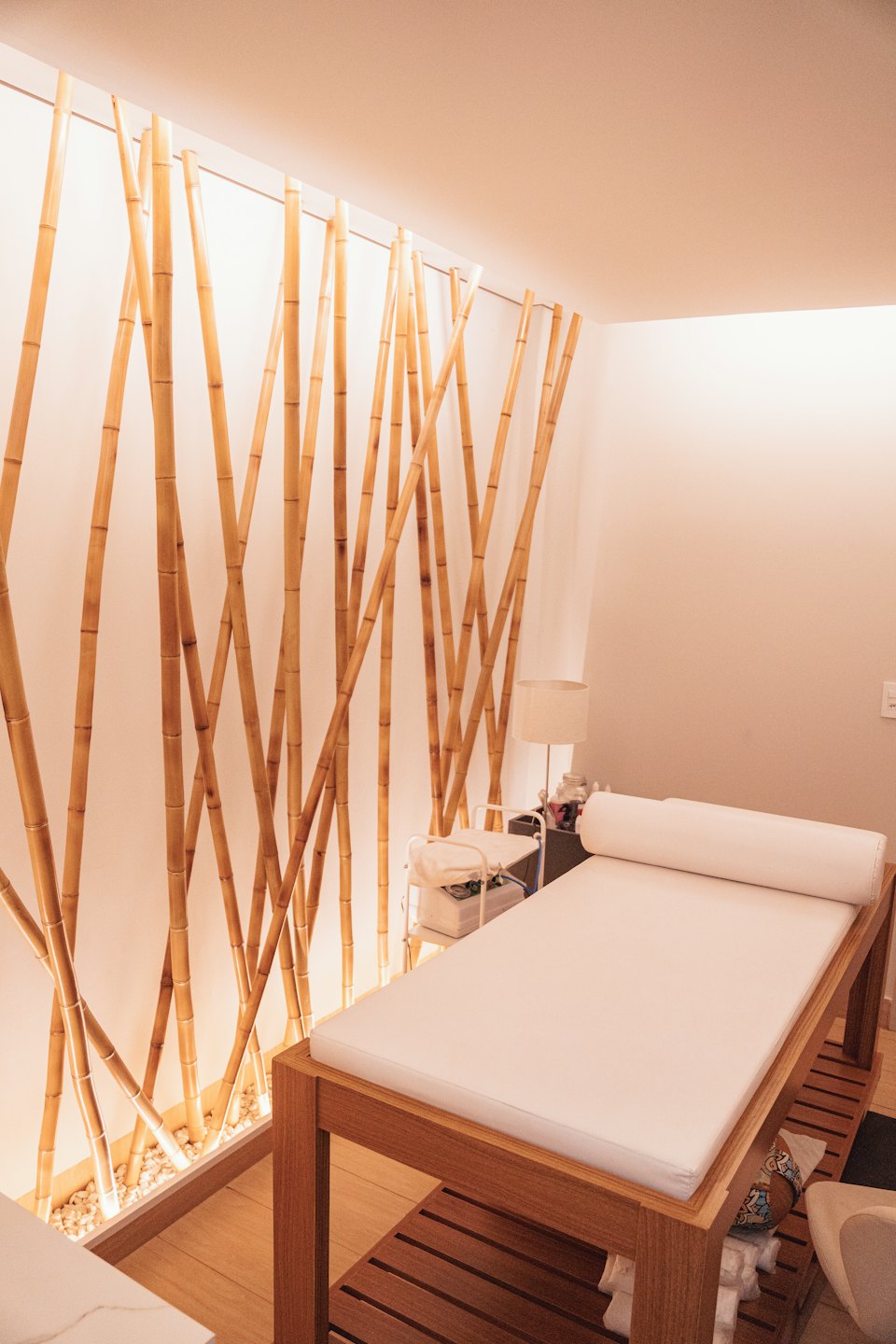 Stanza vuota di una spa con parete di bambù e lettino da massaggio.